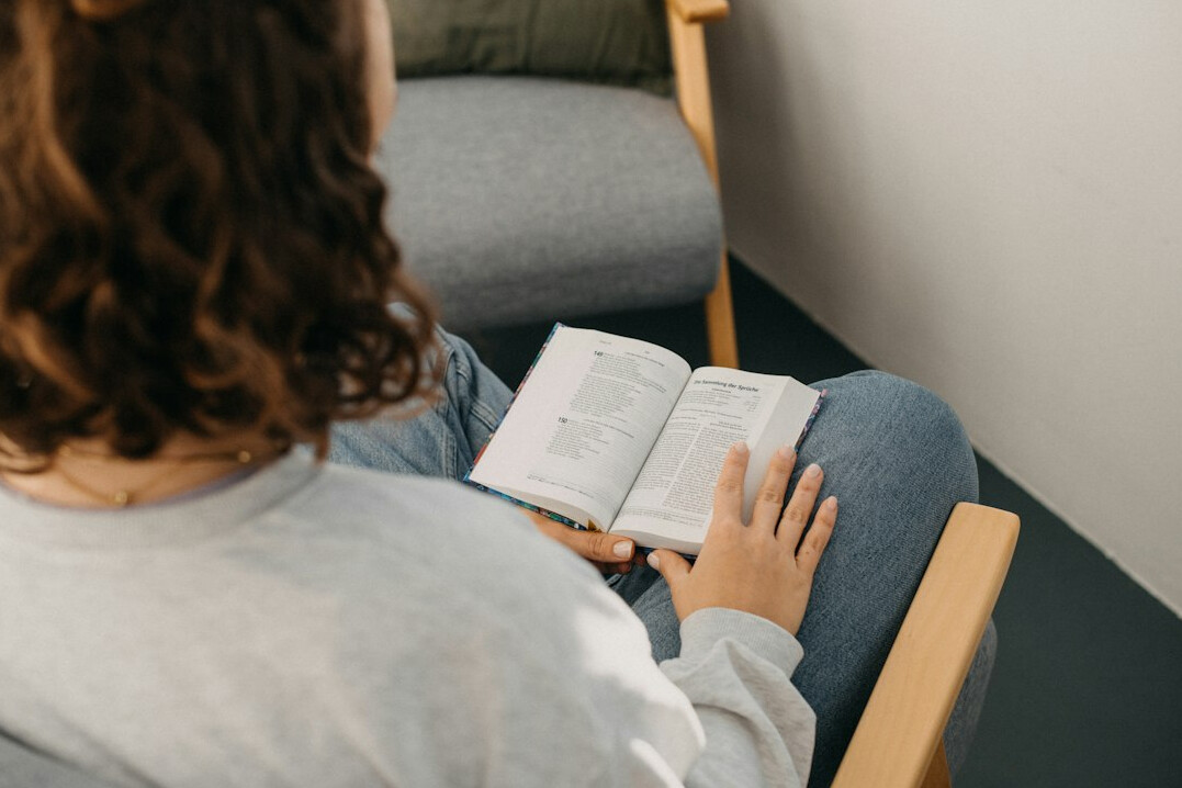 person reading book on couch