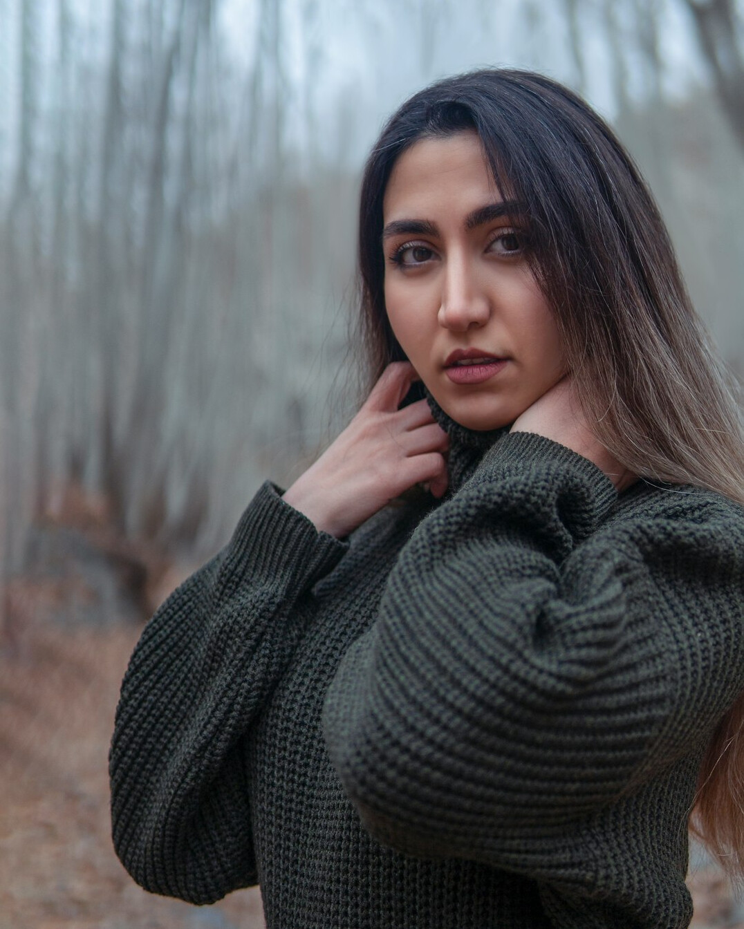 Smiling young woman with long hair in a casual sweater, studio portrait